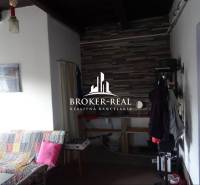 Interiér rodinného domu s pohovkou a věšákem, obložená stěna v pozadí.