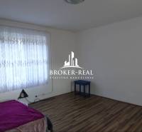 Pokoj s postelí, záclonami a podlahou s dřevěným dekorem v rodinném domě.