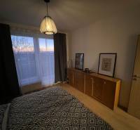 Ložnice s komodou a lampou, podlaha s dřevěným dekorem v dvoupokojovém bytě.