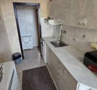 Kuchyně v 3-pokojovém bytě s dlouhou pracovní deskou a světlými skříňkami.