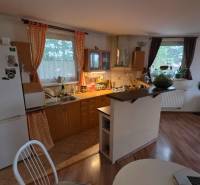 Kuchyně ve 3-pokojovém bytě s podlahou s dřevěným dekorem a jídelním stolem.