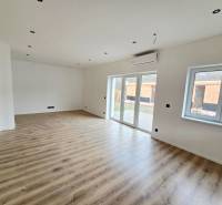 Interiér rodinného domu s podlahou s dřevěným dekorem a velkými okny.