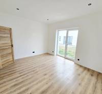 Interiér rodinného domu s podlahou s dřevěným dekorem a velkým oknem do zahrady.