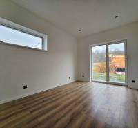 Interiér rodinného domu s podlahou s dřevěným dekorem a velkým oknem.