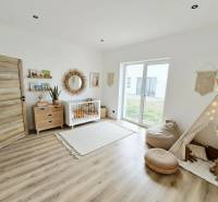 Dětský pokoj v rodinném domě s podlahou s dřevěným dekorem a boho dekoracemi.