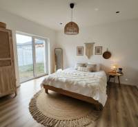 Ložnice s postelí, kulatým kobercem, šatní skříní a podlahou s dřevěným dekorem v rodinném domě.