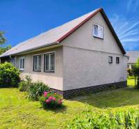 Rodinný dům v Novácích s bílou fasádou a zahradou plnou zeleně.