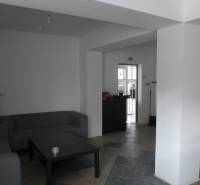 Obývací prostor s šedými pohovkami, stolkem a dlaždicovou podlahou ve skladech a halách.