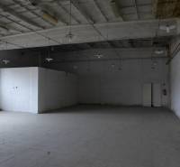 Průmyslový interiér skladu s vysokým stropem a betonovou podlahou.