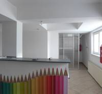 Interiér sklady a haly s recepčním pultem zdobeným barevnými tužkami a požárním hydrantem.