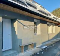 Rodinný dům v Hronci se sněhem na střeše, bílými dveřmi a dřevěnou lavičkou.