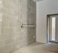 Světlá místnost s nedokončenými stěnami v rodinném domě se vstupními dveřmi.