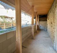 Zastavěný prostor rodinného domu v Hronci se stěnami z kamene a dřevěnými nosníky.