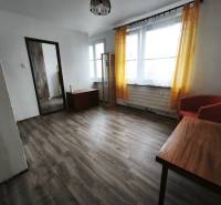 Obývací pokoj v garsonce s podlahou s dřevěným dekorem a žlutými závěsy.