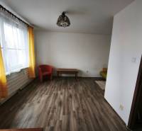 Obývací pokoj v 1-pokojovém bytě s podlahou s dřevěným dekorem a žlutými závěsy.