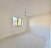 Prostorný, světlý pokoj v rodinném domě s dvojitým oknem a bílými stěnami.