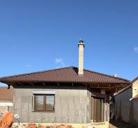 Rodinný dům v Cíferi ve výstavbě s hnědou střechou a komínem.