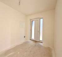 Prázdná místnost s francouzskými dveřmi v rodinném domě, bílé stěny, betonová podlaha.