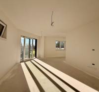 Prostorná místnost v rodinném domě s velkými okny a výhledem do zahrady.