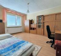 Ložnice v rodinném domě s podlahou s dřevěným dekorem, nábytkem a postelí.