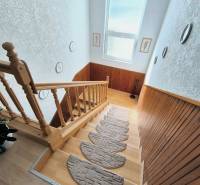 Schodiště s dřevěným zábradlím a dekorací v rodinném domě, podlaha s dřevěným dekorem.