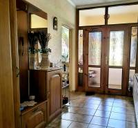 Chodba v rodinném domě se zrcadlem, dekoracemi a prosklenými dveřmi.