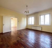 Prostorný pokoj s podlahou s dřevěným dekorem a dvěma velkými okny.