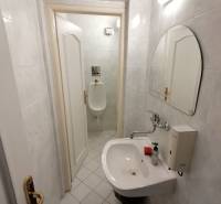 Malá koupelna s umyvadlem a pisoárem v kancelářích.