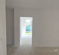 Rodinný dům se světlou místností, bílými stěnami a velkými okny do zahrady.