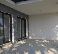 Terasa rodinného domu v Piešťanech s velkými okny a kamenným dekorem.