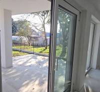Okna a dveře v rodinném domě vedoucí na terasu, výhled na zahradu.