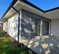 Rodinný dům v Piešťanech s terasou a zahradou, ohraničenou zeleným plotem.