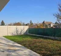 Zahrada rodinného domu v Piešťanech s trávníkem, betonovou terasou a oplocením.