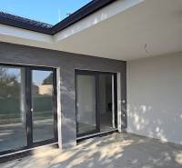 Terasa rodinného domu v Piešťanech s velkými prosklenými dveřmi a šedými stěnami.