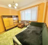 Obývací pokoj ve 4pokojovém bytě s oranžovými stěnami, zelená sedačka a skříňka.