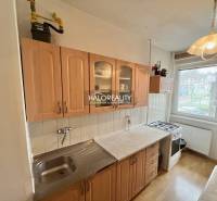 Kuchyň v 4-pokojovém bytě se skříňkami z dřevěného dekoru a plynovým sporákem.