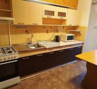 Kuchyně v 3-pokojovém bytě s plynovým sporákem a podlahou s dřevěným dekorem.