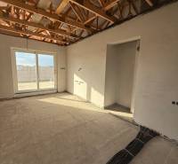 Interiér rodinného domu s odhalenými stropními trámy a přípravou elektroinstalace.