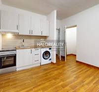 Kuchyně v 1-pokojovém bytě s podlahou s dřevěným dekorem a bílými skříňkami.