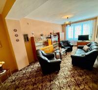 Obývací pokoj v 2-pokojovém bytě s pohovkou a prosklenou vitrínou.