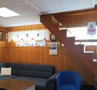 Interiér chaty s dřevěným obkladem, schody, sedačkou a dekoracemi na stěnách.