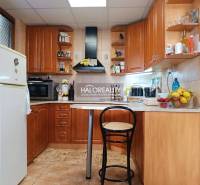 Kuchyně v chatě s dřevěným dekorem, barovým pultem a spotřebiči.