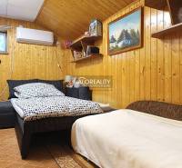 Pokoj v chatě s dřevěným obložením stěn a pohodlnou postelí.