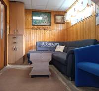 Obývací pokoj v chatě s pohovkou, křeslem a obklady na stěnách.