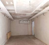 Nezařízená místnost v rodinném domě s bílými stěnami a cihlovou podlahou.