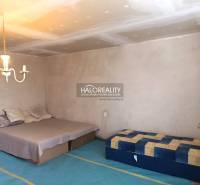 Ložnice v rodinném domě s postelí, matrací, svítidlem a jednoduchým nábytkem.