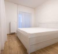 Ložnice v 2-pokojovém bytě s postelí a podlahou s dřevěným dekorem.