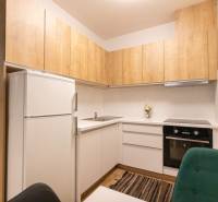 Kuchyně v 2-pokojovém bytě s dřevěným dekorem a bílými skříňkami.