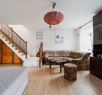 Obývací pokoj v rodinném domě s dřevěným schodištěm, pohovkou, skříňkou a podlahou s dřevěným dekorem.