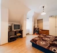 Ložnice v rodinném domě s podlahou s dřevěným dekorem, starší televizí a úložným prostorem.